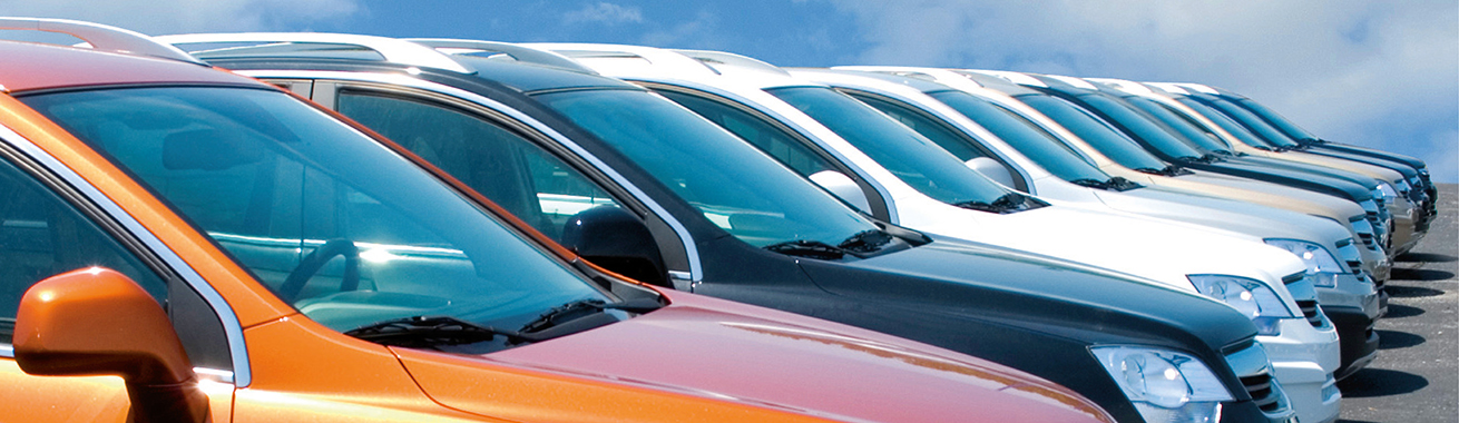 Rad med parkerade bilar i orange, svart, vitt och beige